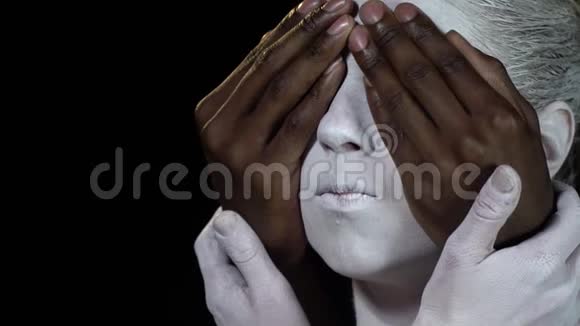 一个黑人用一个穿白色身体艺术的女孩遮住眼睛的侧视视频的预览图