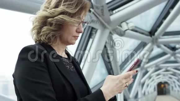 一位迷人的微笑商务女性在商务中心大厅使用智能手机与同事聊天的画像视频的预览图