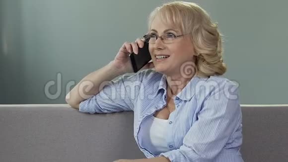 沙发上的老女人用手机说话和孩子说话做母亲视频的预览图