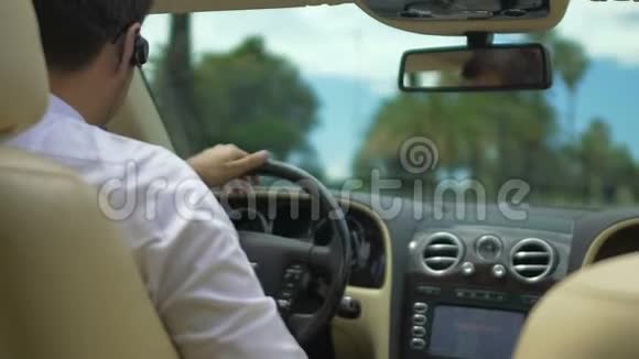 男性驾驶豪华轿车通过耳机交谈忙碌的商人视频的预览图