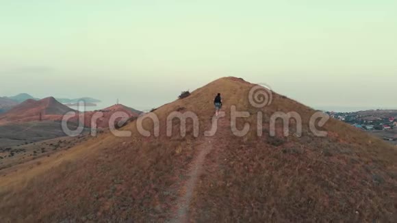黄昏时分一个背着背包的人在山谷的背景下漫步视频的预览图