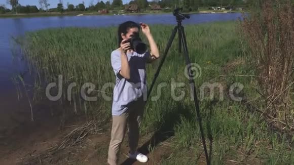 在湖边使用专业照相相机的女人视频的预览图