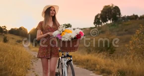 穿着中规中矩的女孩在田野里骑着自行车和鲜花视频的预览图