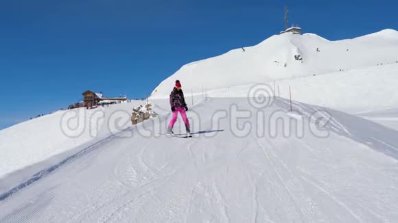 滑雪女新手在山上滑雪坡上小心放慢滑雪速度视频的预览图