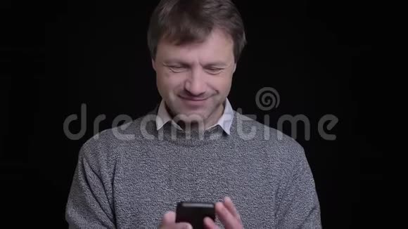 一个成年白种人的特写镜头他用手机发短信在镜头前微笑视频的预览图