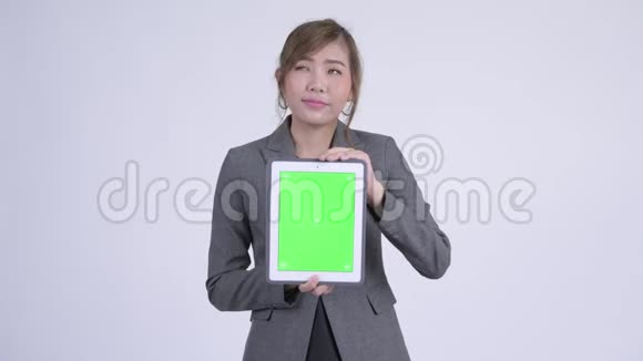 年轻快乐的亚洲女商人一边思考一边展示数码平板电脑视频的预览图