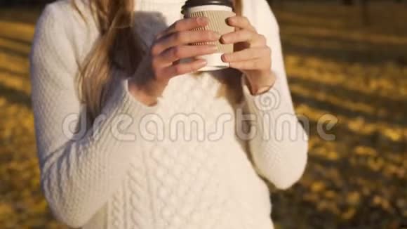 美丽的女孩在秋日的阳光下享受温暖的饮料在公园里散步视频的预览图