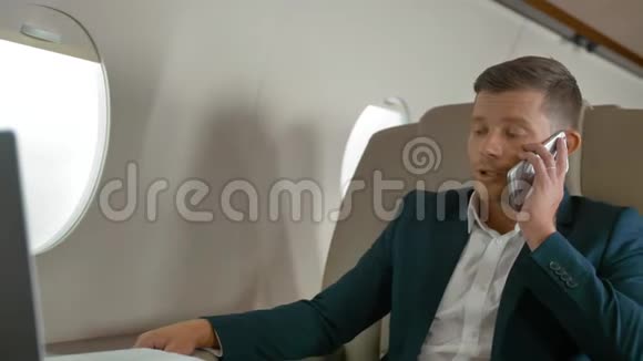 成熟的商人在飞机上用手机说话视频的预览图