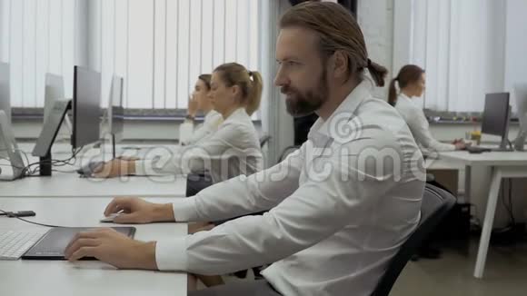 有脊柱侧凸的商人在办公室用电脑工作视频的预览图