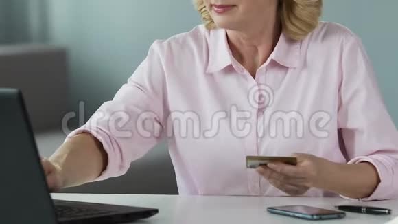 成熟女性在笔记本电脑上插入卡号在线购物特写视频的预览图