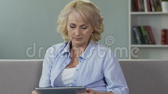 老年女性戴眼镜看平板电脑看网络报纸视频的预览图