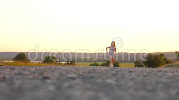 小女孩在自然生活方式户外日落时在沥青上尽情奔跑视频的预览图