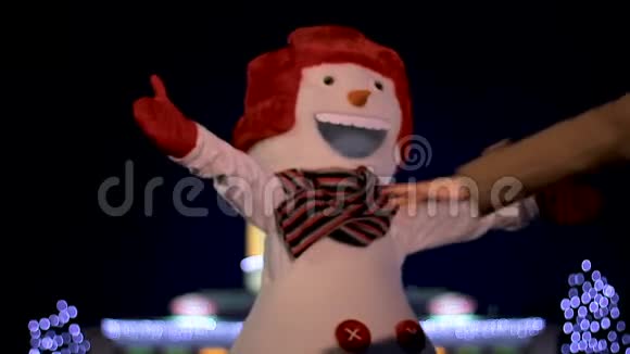 快乐的女孩在节日的灯光下和可爱的圣诞雪人拥抱和跳舞视频的预览图