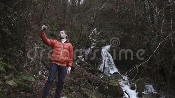 成年胡须男在秋天的森林里用智能手机自拍视频的预览图