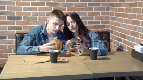 可爱的情侣在咖啡馆里聊天吃汉堡包视频的预览图