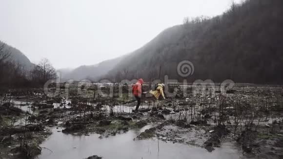 男人和他的朋友穿着秋装试图在雨中穿越沼泽视频的预览图