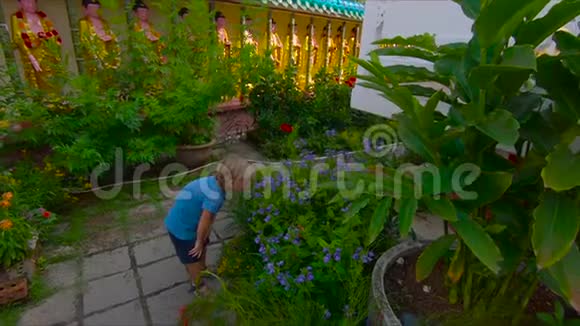 马来西亚槟城一座KekLokSi神庙的花园里男孩闻到了鲜花的味道视频的预览图