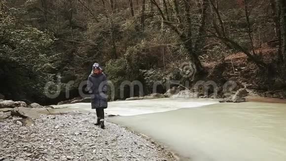 在阴天的秋天独自悲伤的女孩在森林河边散步视频的预览图