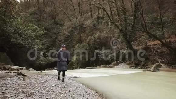 旅游女孩正走在流经森林的小河沿岸视频的预览图