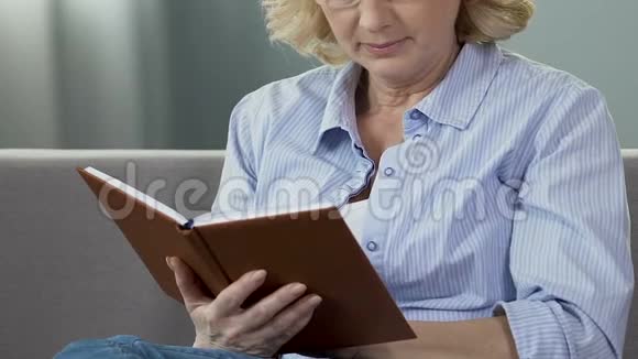 退休妇女坐在沙发上看书热衷于读书闲暇时间视频的预览图