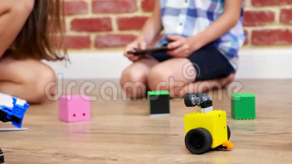 特写镜头无线电控制的机器人在地板上移动小天才孩子们在上面玩电子机器人汽车现代玩具视频的预览图
