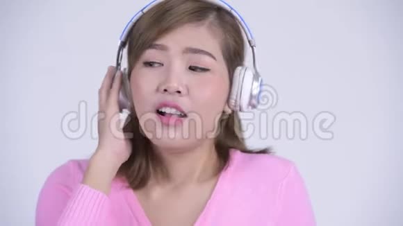 年轻快乐的亚洲女人边听音乐边思考的脸视频的预览图