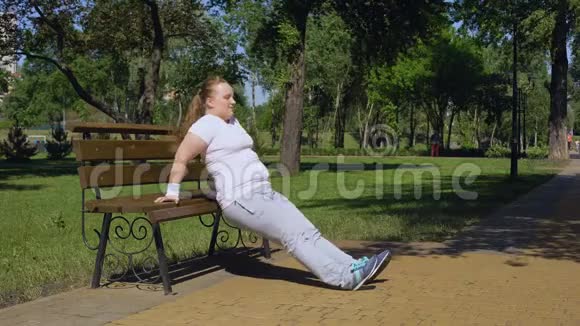 肥胖女孩在公园的长凳上锻炼勤奋任何地方都有运动视频的预览图