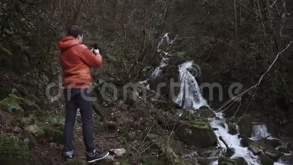旅行者在秋天寒冷的一天在森林里用手机拍摄视频视频的预览图
