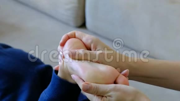 女士双手为白人男孩做足底按摩儿童特写按摩视频的预览图