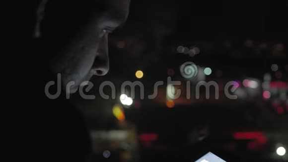 年轻人晚上在模糊的城市灯光面前使用智能手机手机应用技术视频的预览图