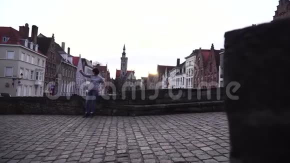 在比利时布鲁日市的背景下女游客在智能手机上自拍视频的预览图