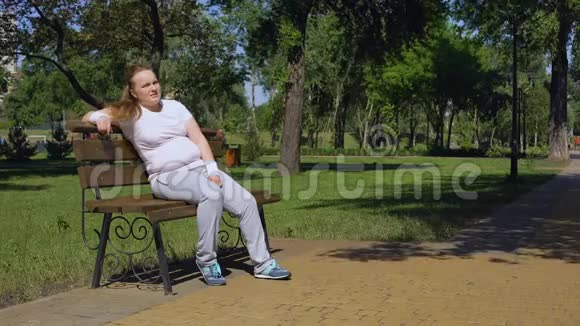 慢跑后胖女孩精疲力竭在长凳上休息片刻以对抗肥胖视频的预览图