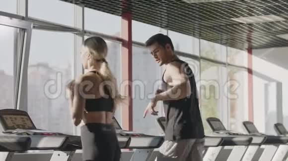 健身情侣一起在健身房的跑步机上跑步视频的预览图