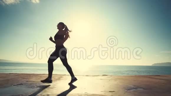 日出时在海边奔跑的女人强壮的运动员早上做运动视频的预览图