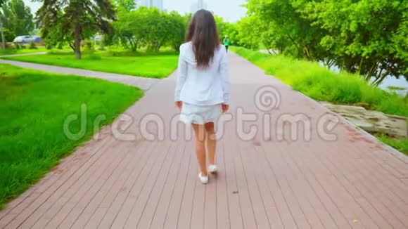 快乐的黑发女郎带着绿色的夏日自然景观漫步城市视频的预览图