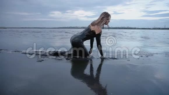 爬行可爱的滑头金发被黑泥浸湿看起来像石油视频的预览图
