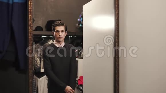 帅哥正在设计师商店的陈列室里试穿一件黑色柔软的毛衣视频的预览图