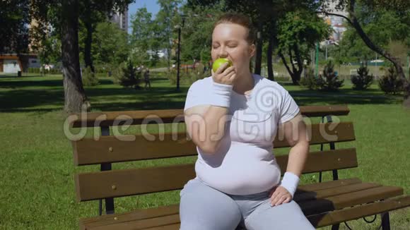 肥胖女孩慢跑后吃苹果健康饮食适当的午餐维生素视频的预览图