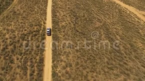 背面鸟瞰大银色SUV在日落前的草原上行驶视频的预览图