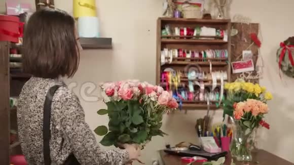 花店女在花束中加入玫瑰花供顾客在工作间订购视频的预览图
