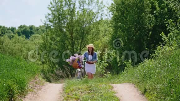 戴着帽子的可爱女孩骑着自行车在大自然中旅行视频的预览图