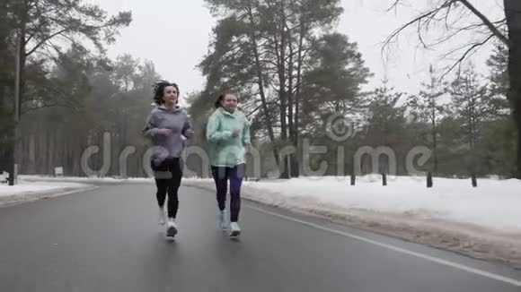 快乐的年长和年轻的高加索女人在冬天的雪地公园里奔跑交谈和微笑前面跟射弹视频的预览图