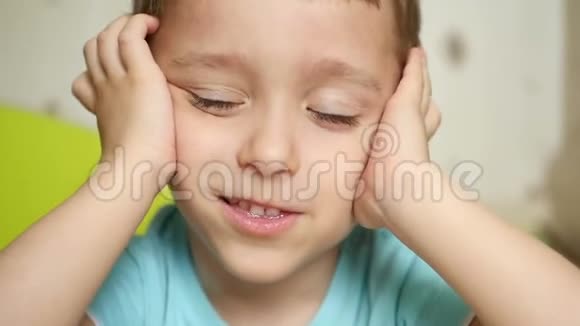 一个喜笑颜开的孩子看着镜头双手抱在脑后闭上耳朵特写镜头视频的预览图