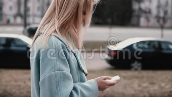 穿着蓝色外套的慢动作金发女人发短信侧视女孩在发信息生活方式高的生活节奏视频的预览图