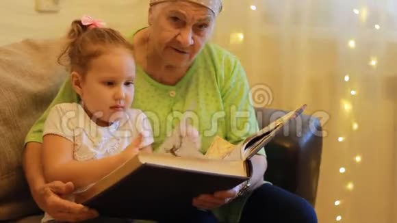 外婆和孙女一起读童话书祖母拥抱她的孙女视频的预览图