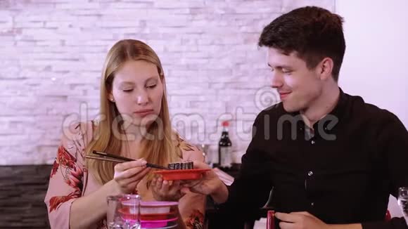 一对年轻夫妇在寿司餐厅吃新鲜的寿司从自助餐视频的预览图