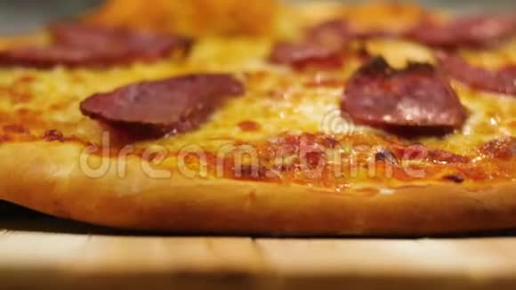 新鲜出炉的热辣可口的意大利香肠披萨摆在木桌上旁边是一个模糊的男人或女人的厨师视频的预览图