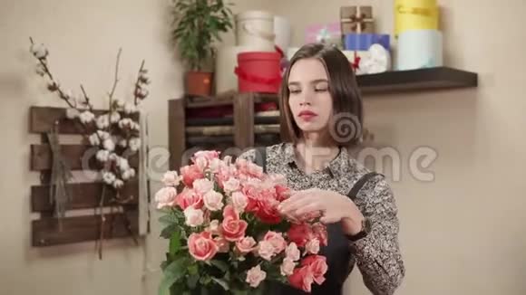 鲜花沙龙的年轻女售货员正捧着一大束玫瑰花束视频的预览图