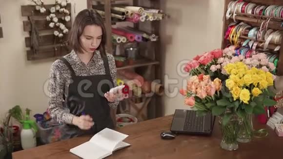 花卉工作室的女售货员正指望着一台智能手机计算器和写作视频的预览图