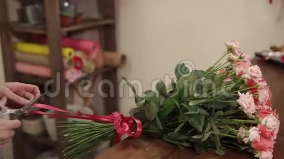女售货员正在剪一束鲜花上的红色带子然后从桌子上拿过来视频的预览图